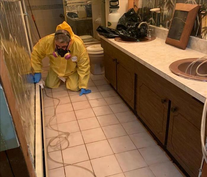 A SERVPRO technician wearing PPE to continue cleaning the bathroom
