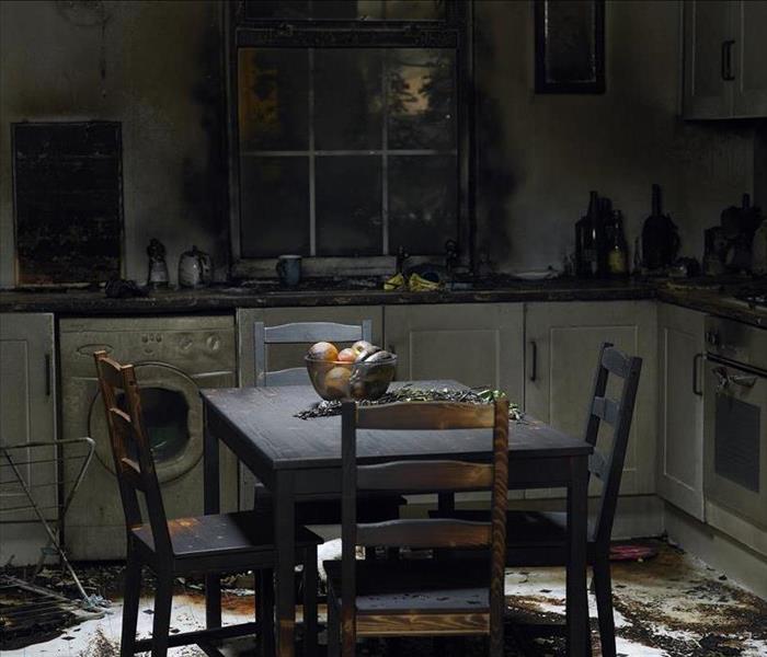 Kitchen with smoke and soot damage.  White cabinets darkened by soot and ash.  Wood table and chairs coated in ash.