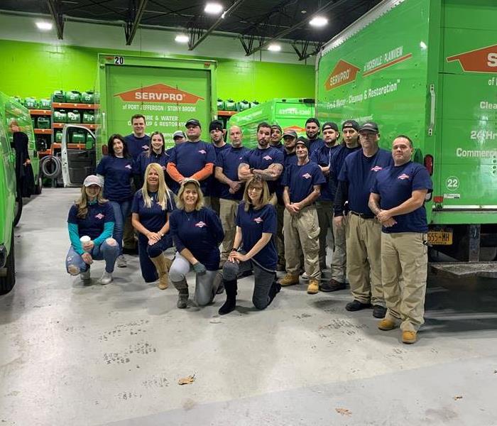 A large group of SERVPRO employees standing in front of several SERVPRO vehicles. 