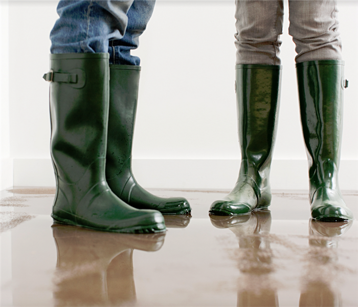 two people in rain boots standing on a waterlogged carpet