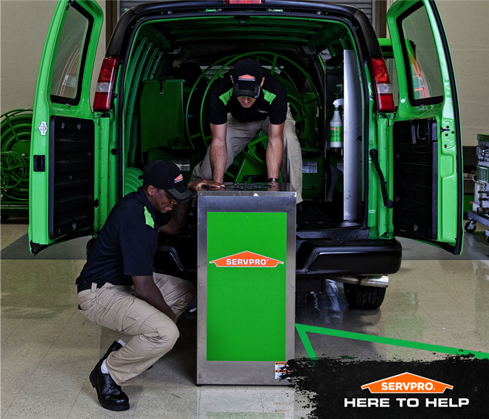 SERVPRO technicians  unloading water extracting equipment from SERVPRO van.